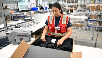 GEODIS women employee packing a jacket in a box-EDELSON Josh