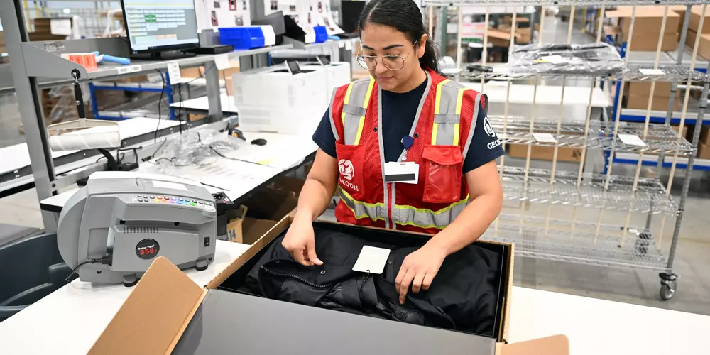 GEODIS women employee packing a jacket in a box-EDELSON Josh